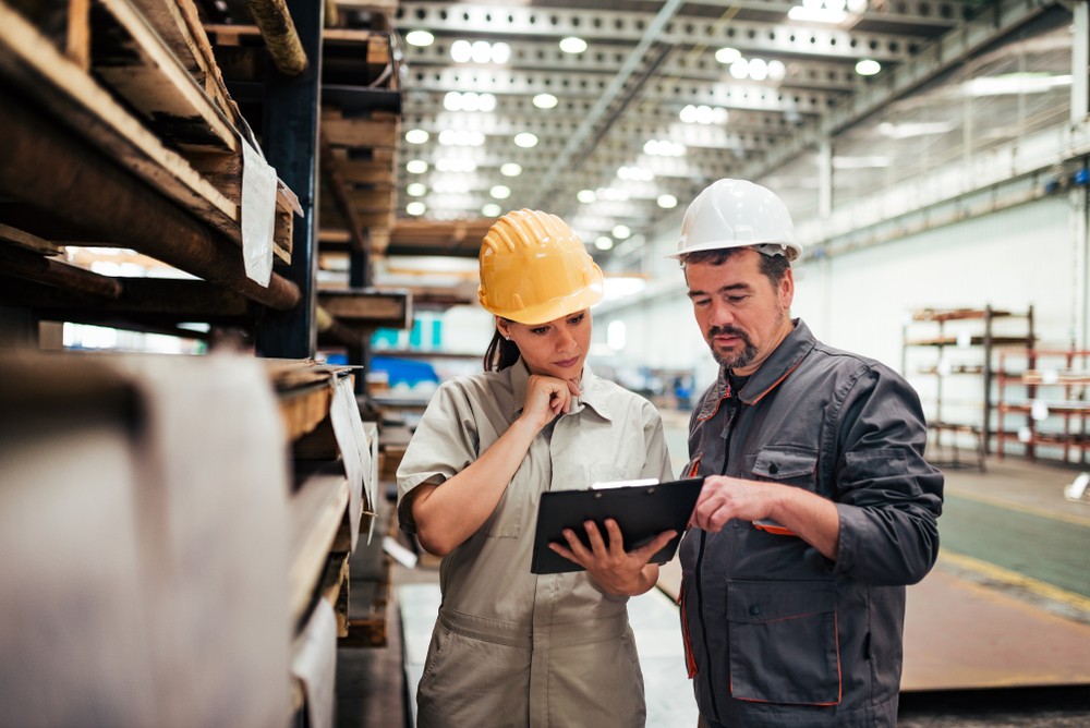 Two workers in a manufacturing setting consulting about safety